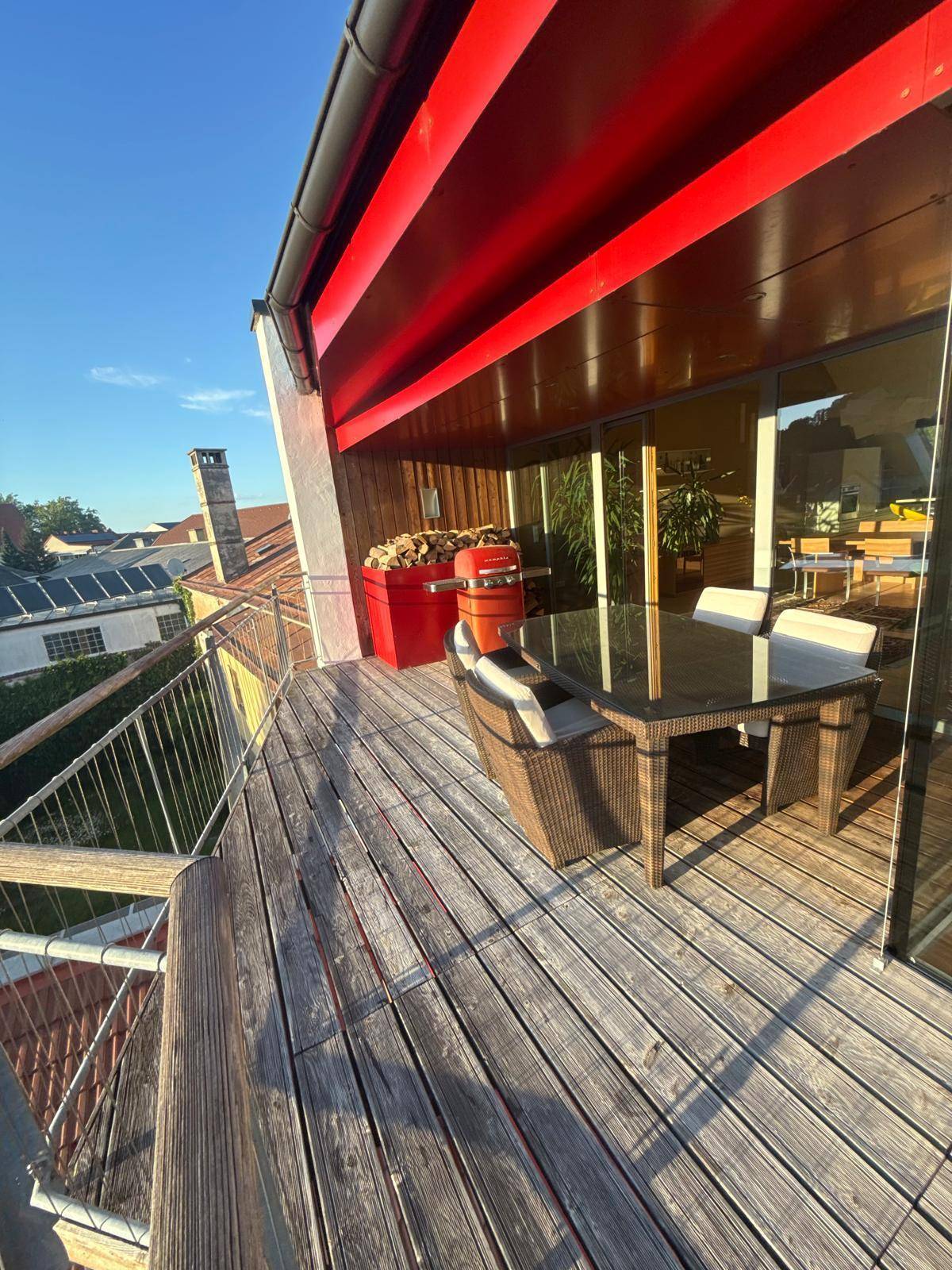 Geräumiger Holzbalkon mit Gartenmöbeln und Grill, ideal für entspannte Stunden im Freien.