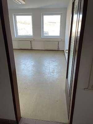 Heller, leerer Raum mit hellem Boden, zwei Fenstern und Heizkörpern, bereit zur Nutzung.