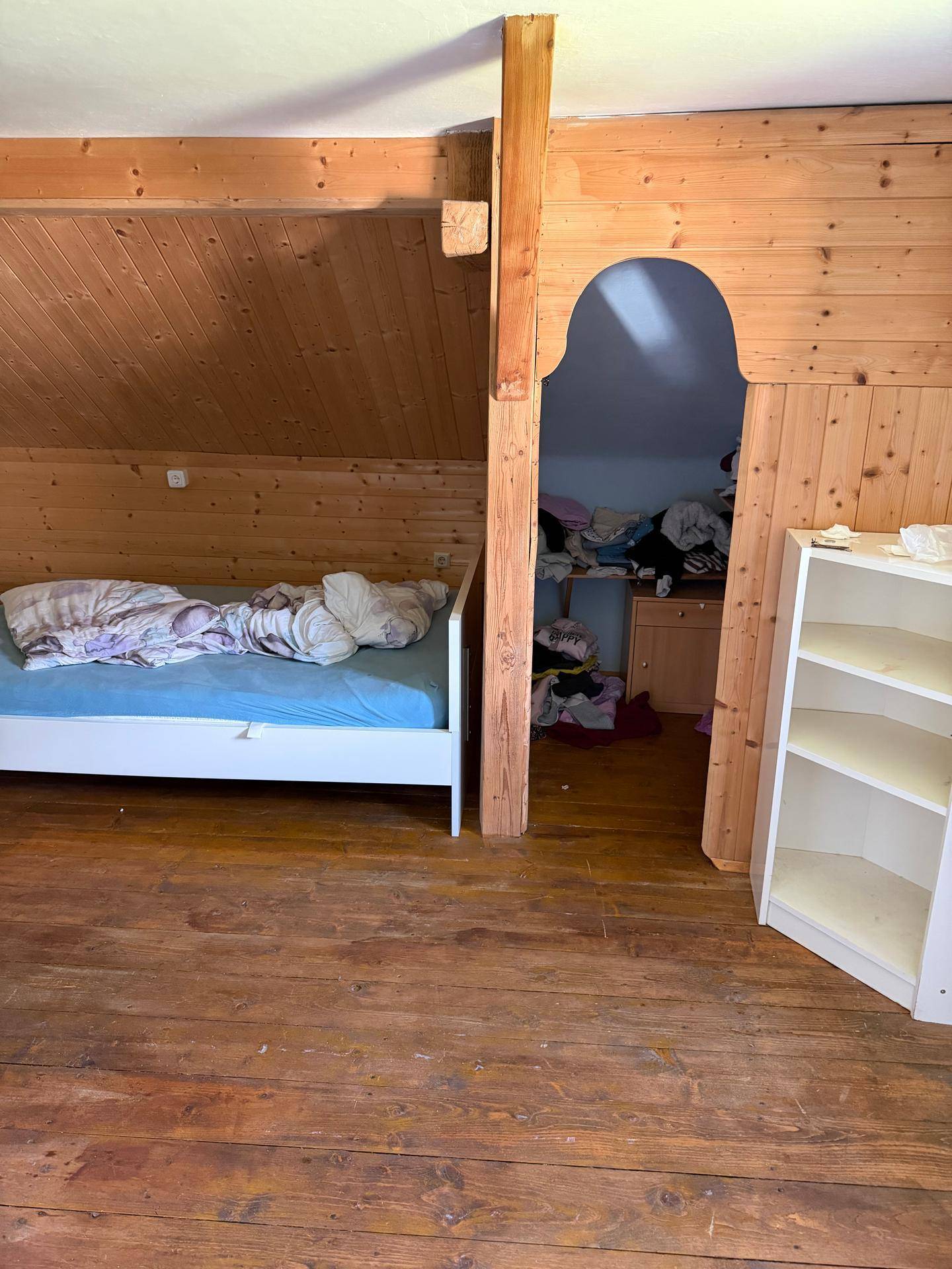Schlafzimmer im Dachgeschoss mit Holzvertäfelung und schrägen Wänden.