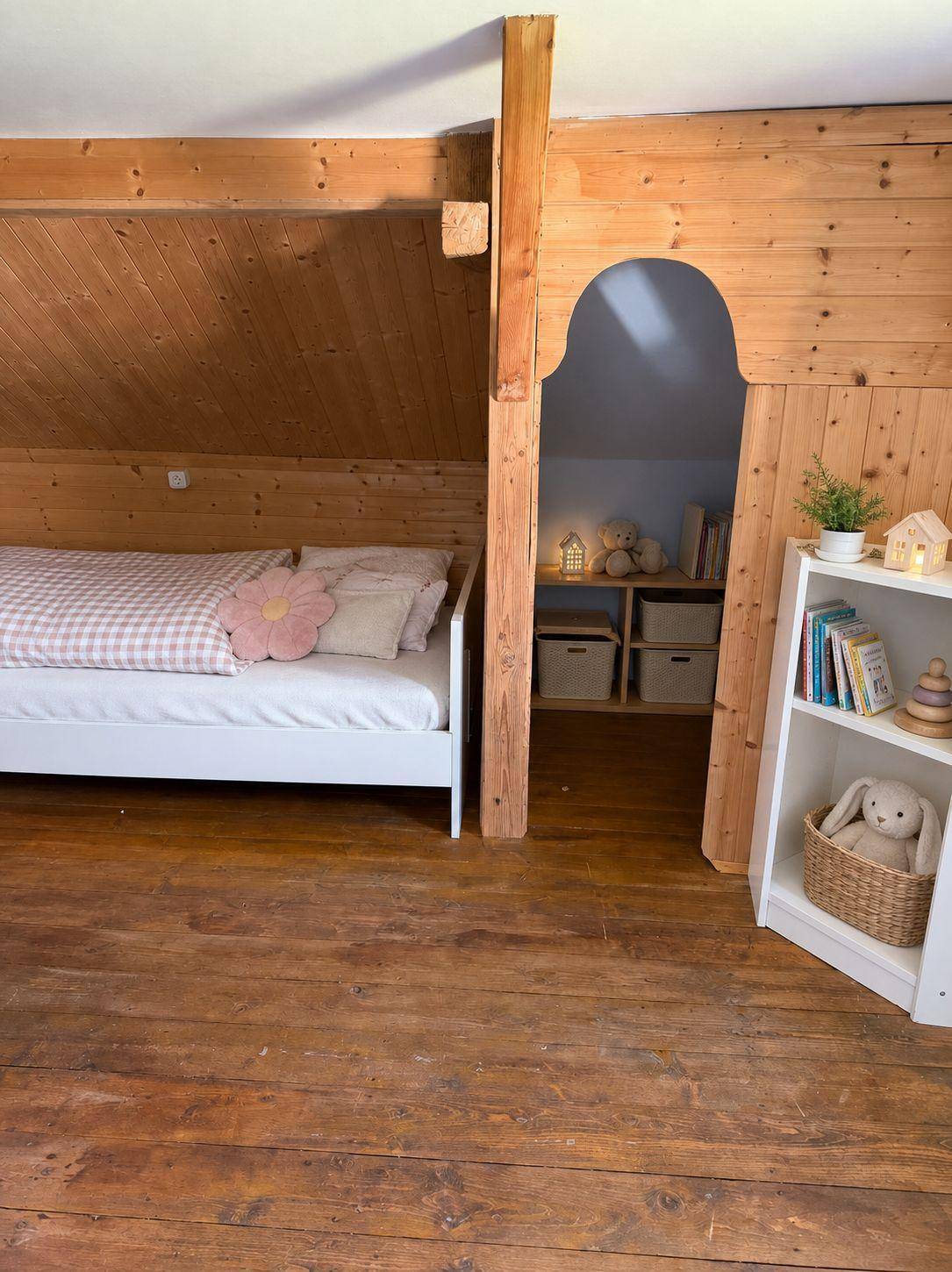 Gemütliches Schlafzimmer im Dachgeschoss mit Holzvertäfelung und schrägen Wänden.