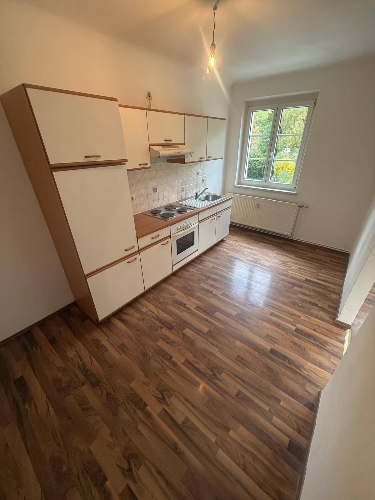 Leere Küche mit älteren Einbauschränken, Herd und Spüle, bereit zur Renovierung.