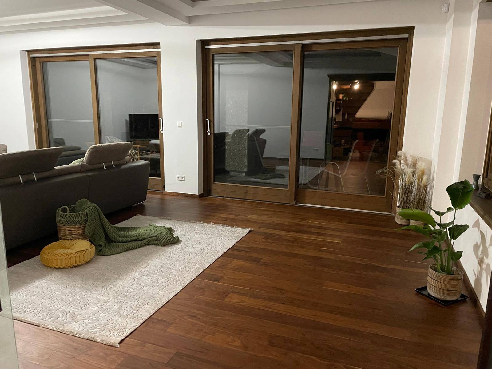 Geräumiges Wohnzimmer mit dunklem Holzboden und großen Schiebetüren, die viel Licht hereinlassen.