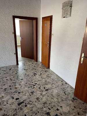 Flur mit Terrazzoboden und mehreren Holztüren, die zu verschiedenen Räumen führen.