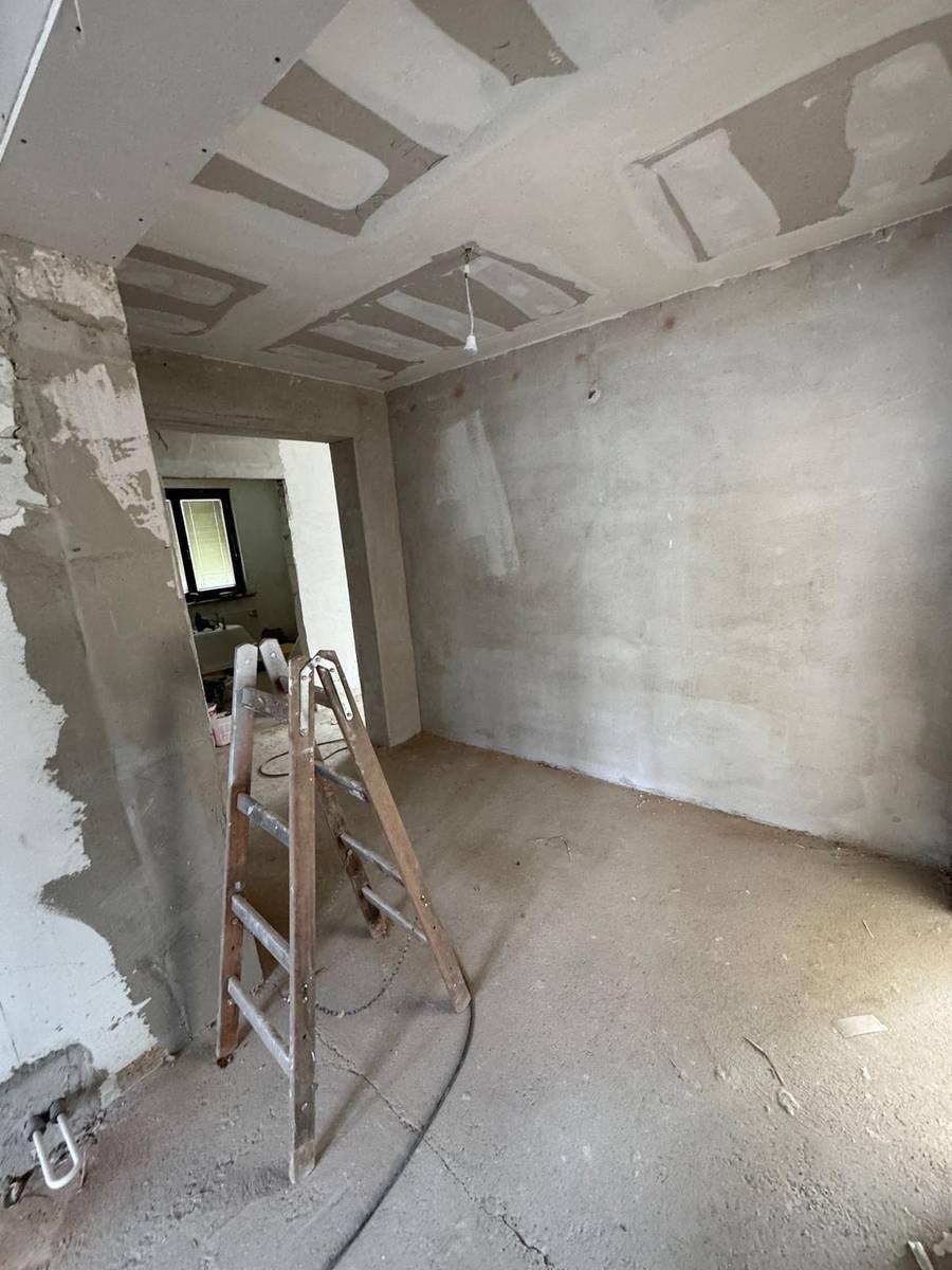 Innenraum im Rohbau mit unverputzten Wänden und Decken, bereit für den weiteren Ausbau.