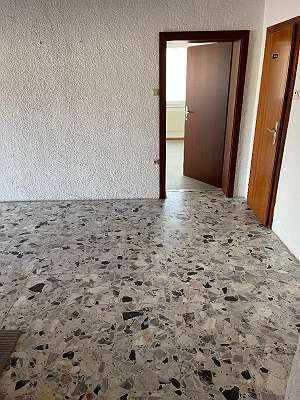 Flur mit Terrazzoboden und Holztüren, der den Zugang zu angrenzenden Räumen ermöglicht.
