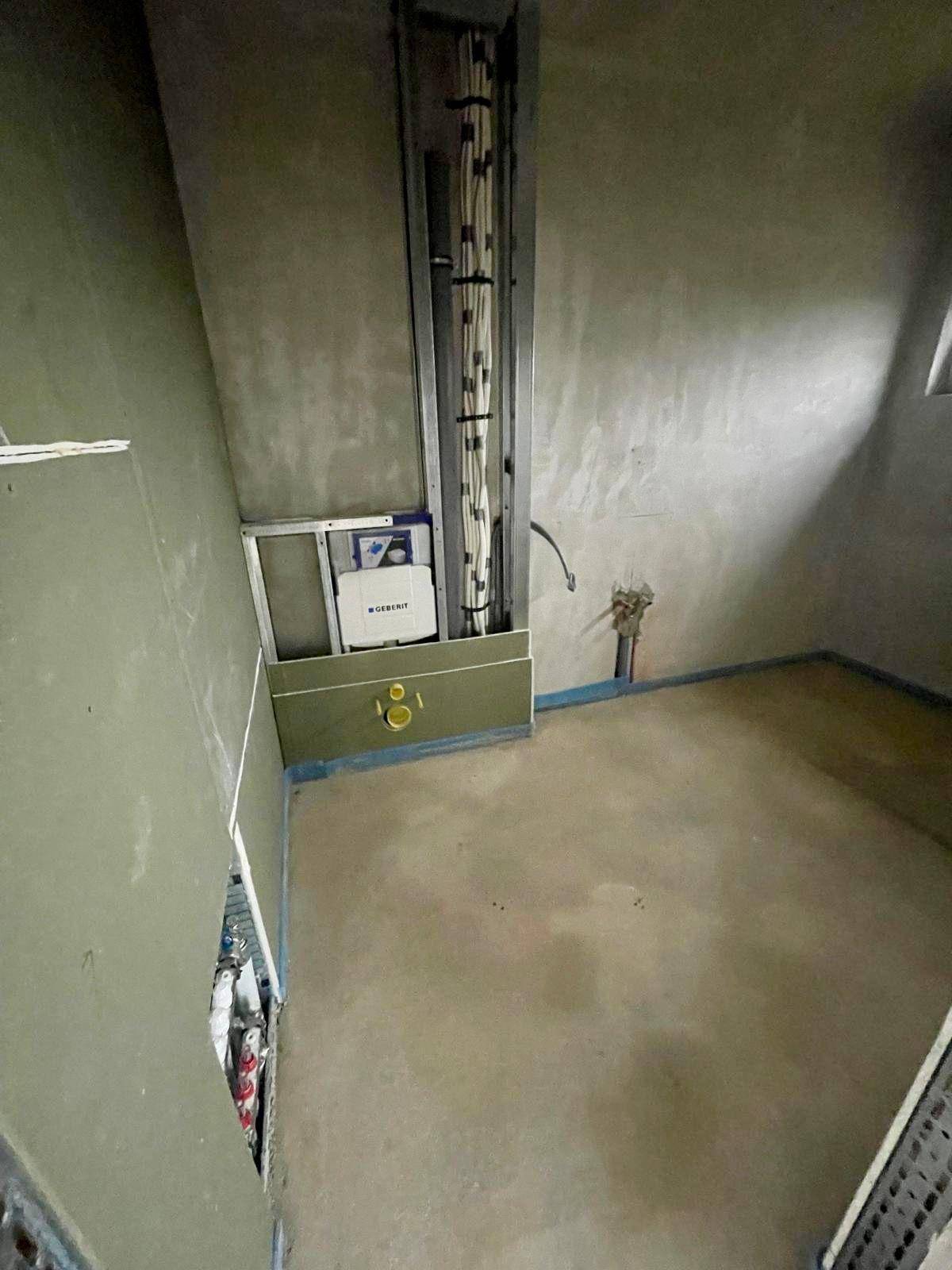 Rohbau-Raum mit vorbereiteter Toilette und Installationen, bereit für die Fertigstellung.