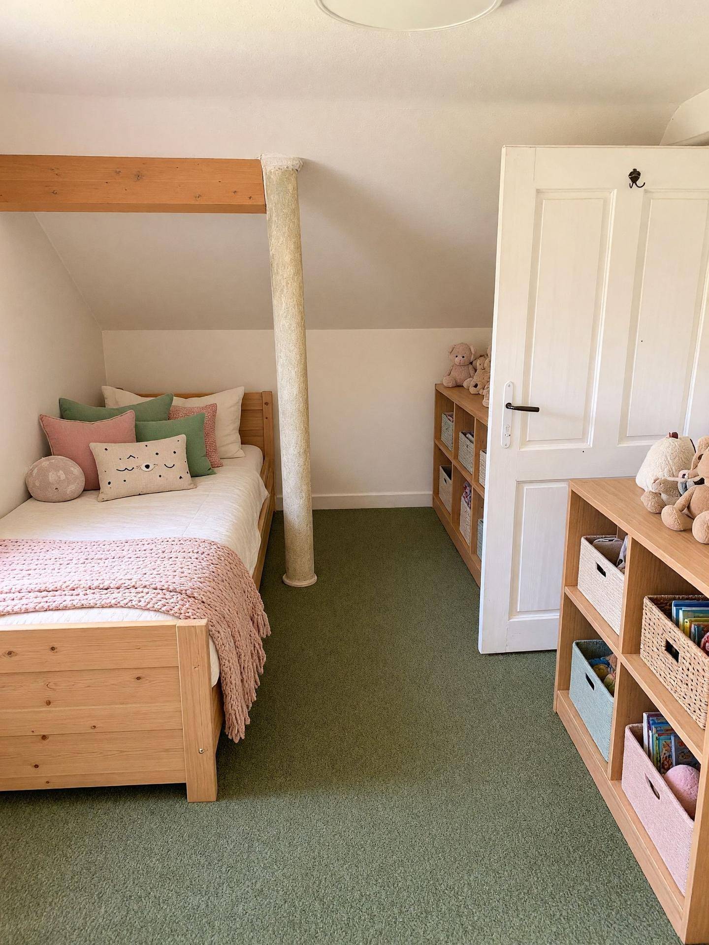 Helles Kinderzimmer im Dachgeschoss mit Teppichboden und Holzbett.