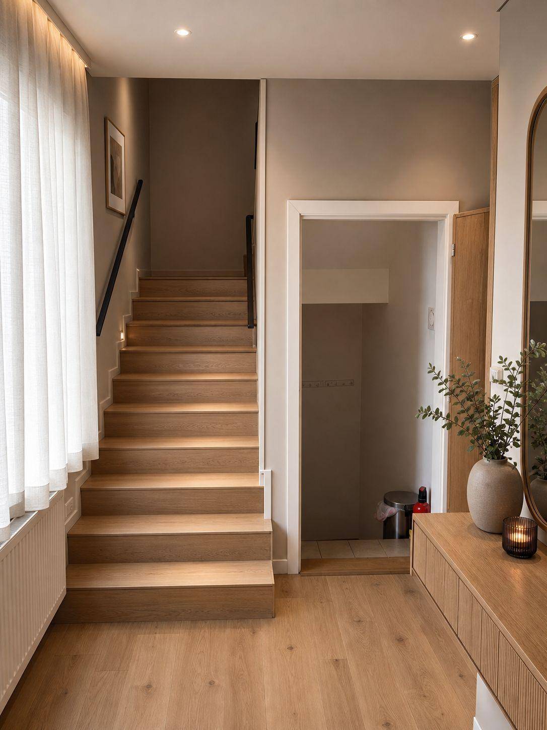 Moderner Flur mit Holztreppe ins Obergeschoss und praktischem Stauraum darunter.