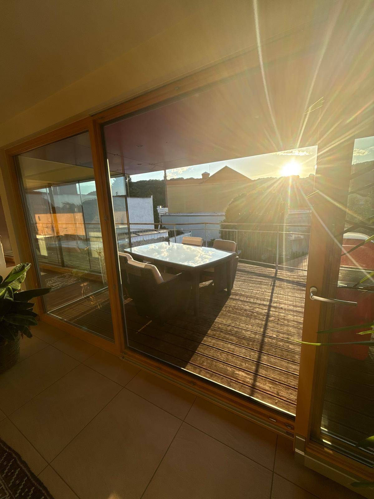 Heller Innenraum mit großen Glasschiebetüren, die auf einen sonnigen Balkon mit Stadtblick führen.