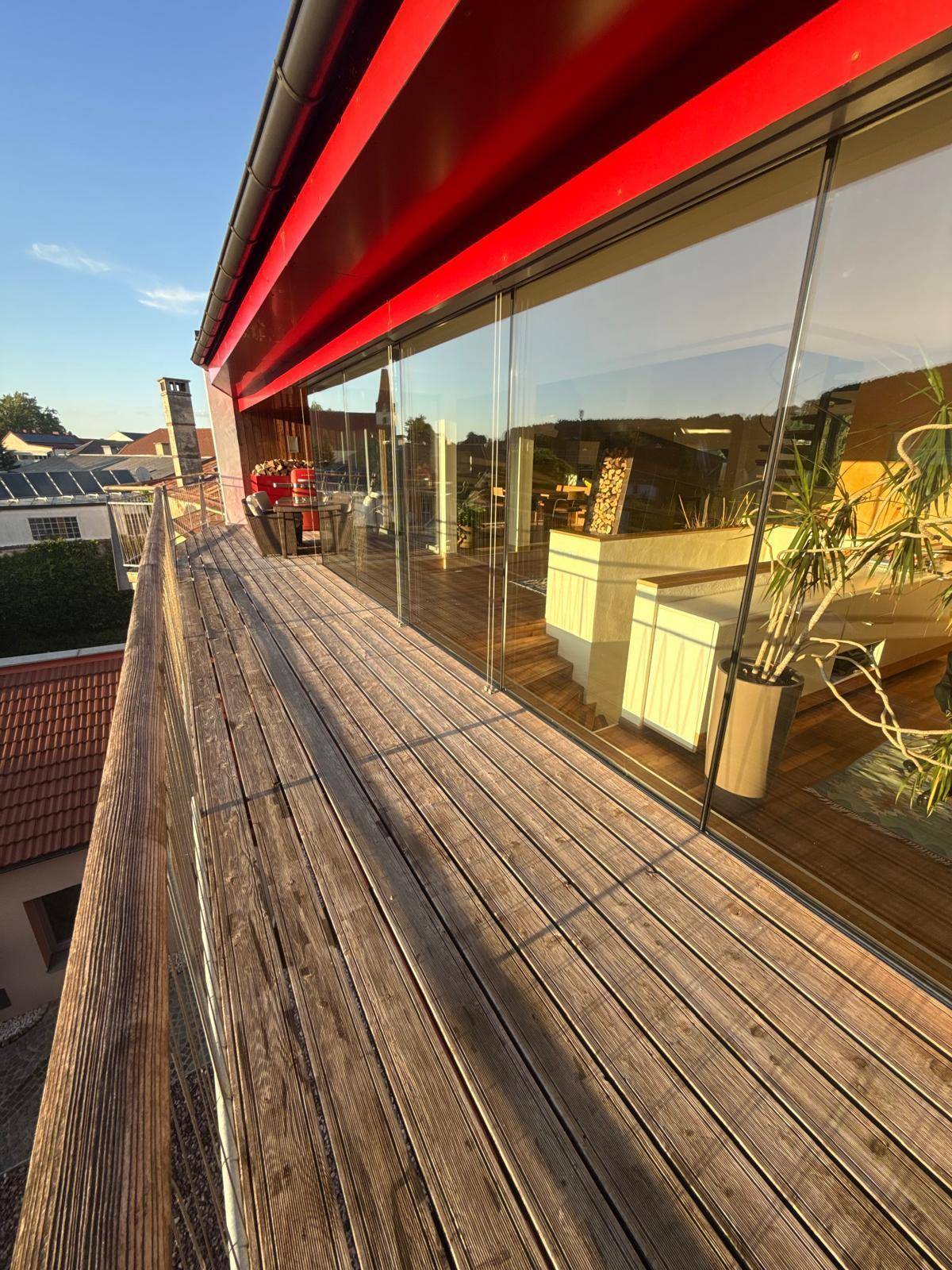 Großer Holzbalkon mit rotem Vordach und weitem Blick über die Stadt.