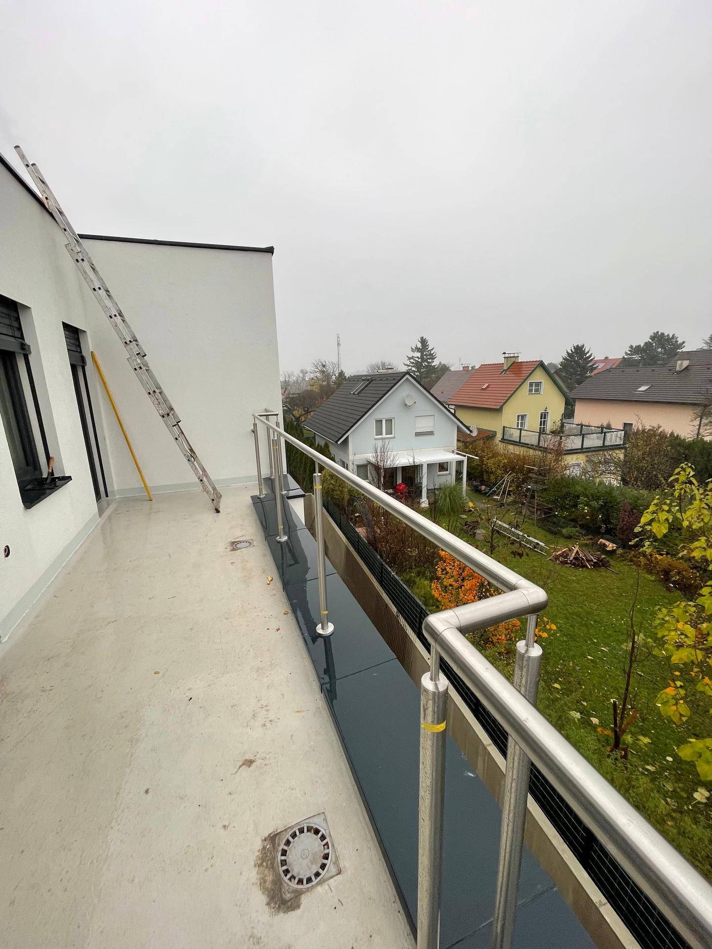 Große Terrasse mit Edelstahlgeländer und Blick auf die Nachbarschaft und Gärten.