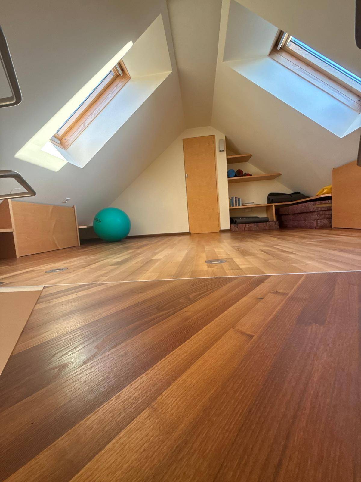 Heller Dachbodenraum mit Holzboden und zwei Dachfenstern, die viel Licht spenden.
