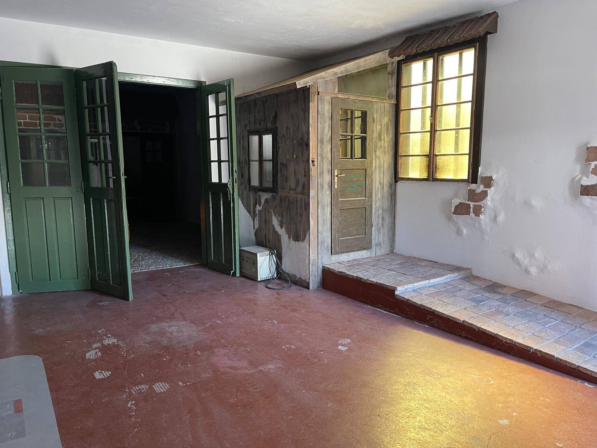 Innenraum mit rotem Boden, einer Rampe und einer kleinen Holzhütte, die einen rustikalen Charme verleiht.