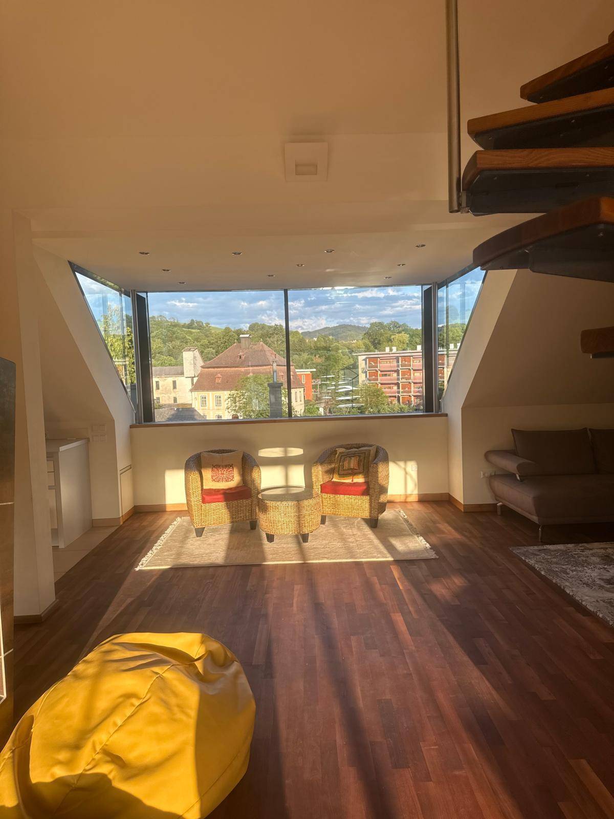 Gemütliches Wohnzimmer mit Holzboden, Panoramablick und einer eleganten Wendeltreppe.