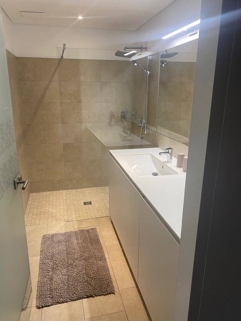 Modernes Badezimmer mit begehbarer Dusche, großem Spiegel und minimalistischem Design.