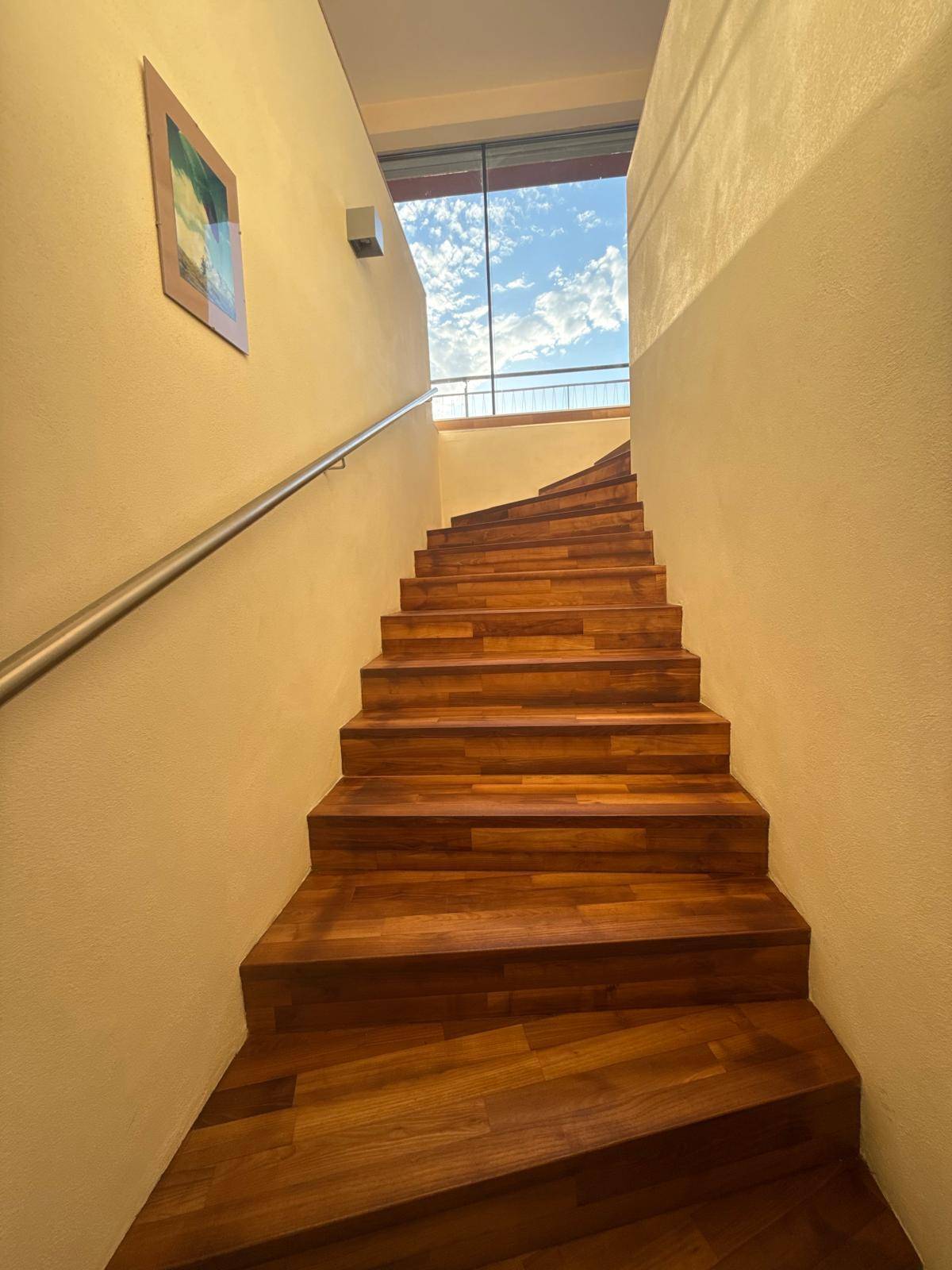 Elegante Holztreppe mit viel Tageslicht, die zu den oberen Etagen führt.