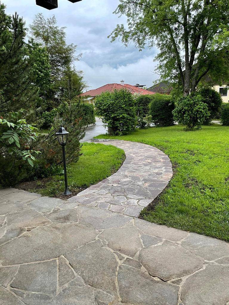 Gepflegter Garten mit Steinweg und üppiger grüner Bepflanzung, ideal für Spaziergänge.