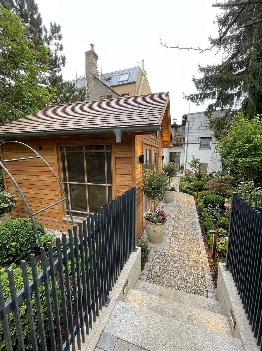 Ein gepflegter Gartenbereich mit einem Holzhaus und Steintreppen, umgeben von üppiger Bepflanzung.