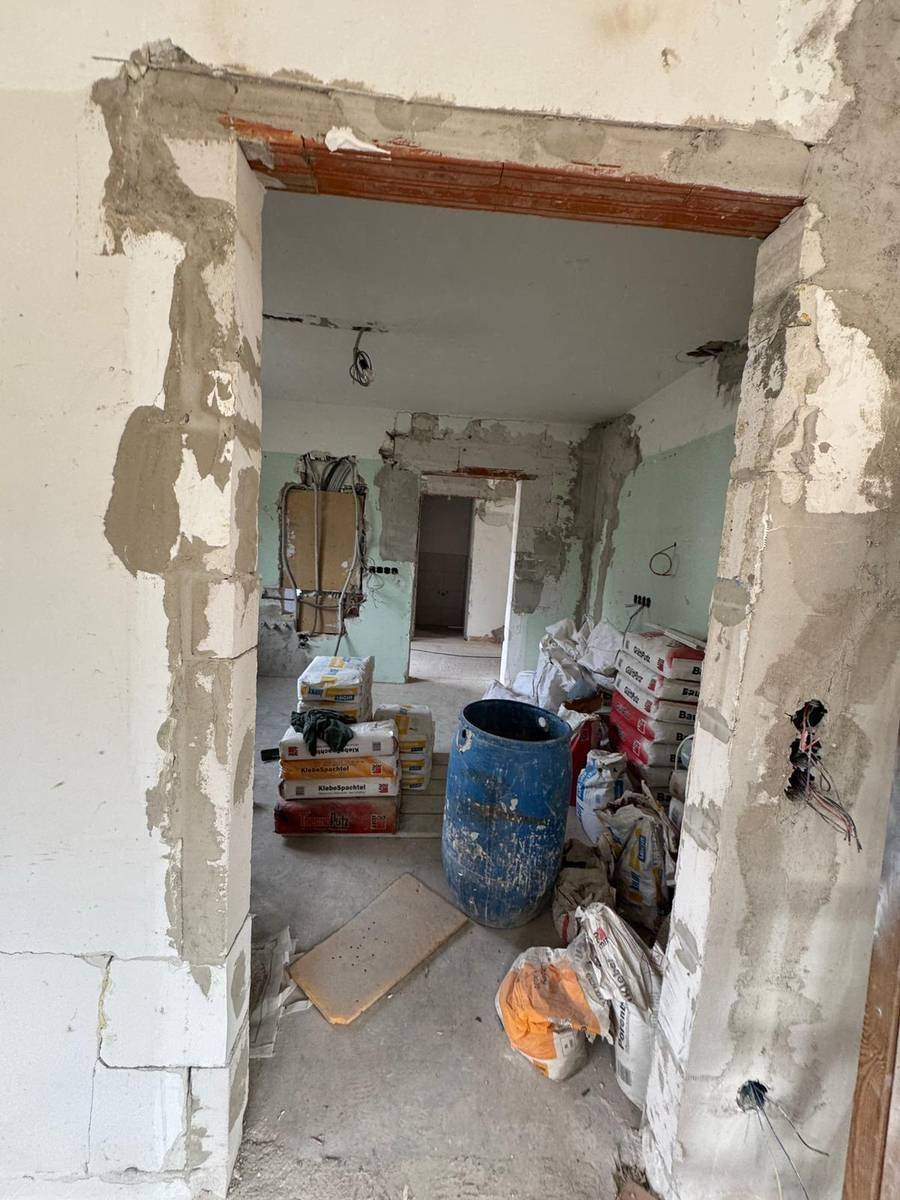 Flur im Rohbau mit offenen Türrahmen und Baumaterialien, bereit für den weiteren Ausbau.