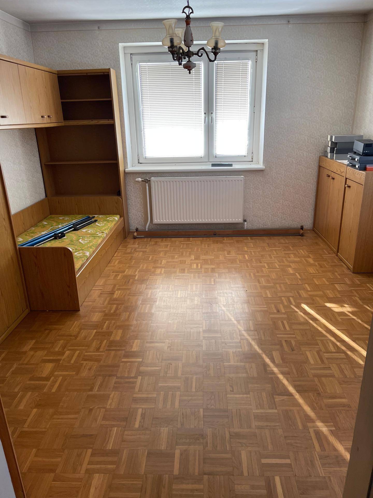 Schlafzimmer mit Parkettboden, Fenster und Einbauschränken.