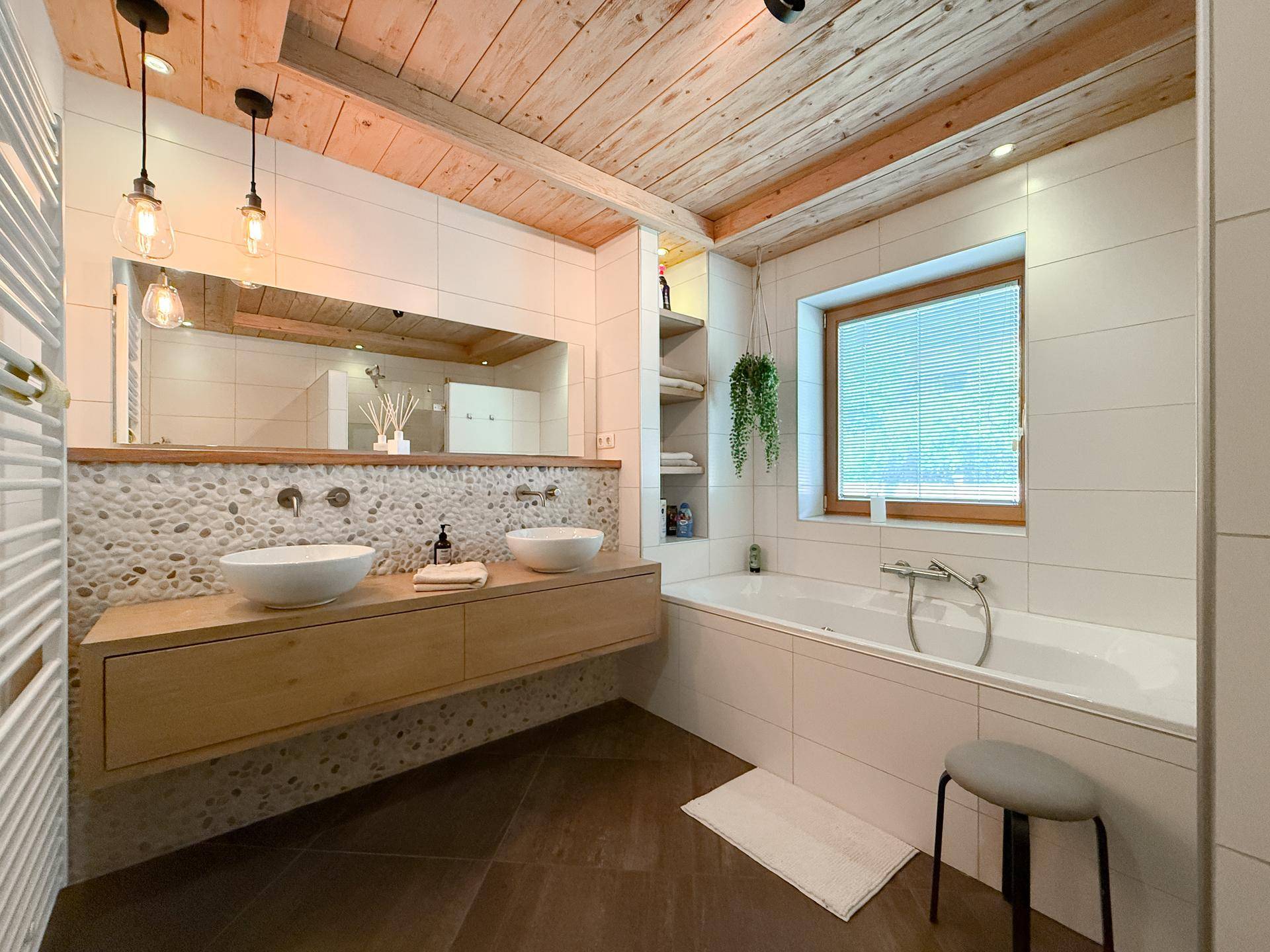 Modernes Badezimmer mit Doppelwaschbecken, Badewanne und Naturstein-Akzenten.