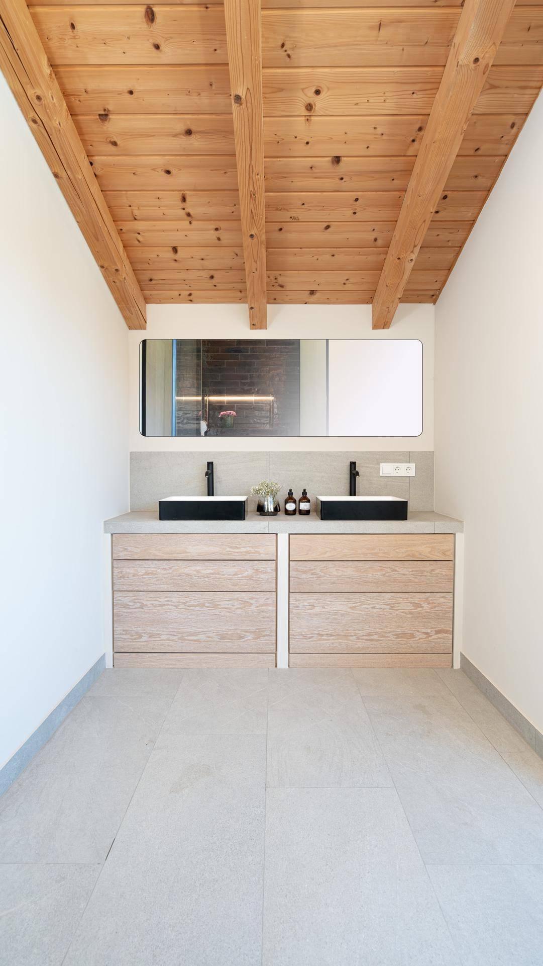 Geräumiges Badezimmer mit Doppelwaschtisch, Holzbalkendecke und modernen Armaturen.