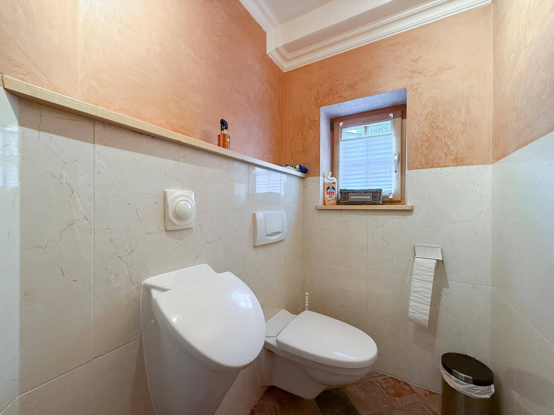 Modernes Gäste-WC mit Wand-WC, Bidet und Fenster für natürliche Belüftung.