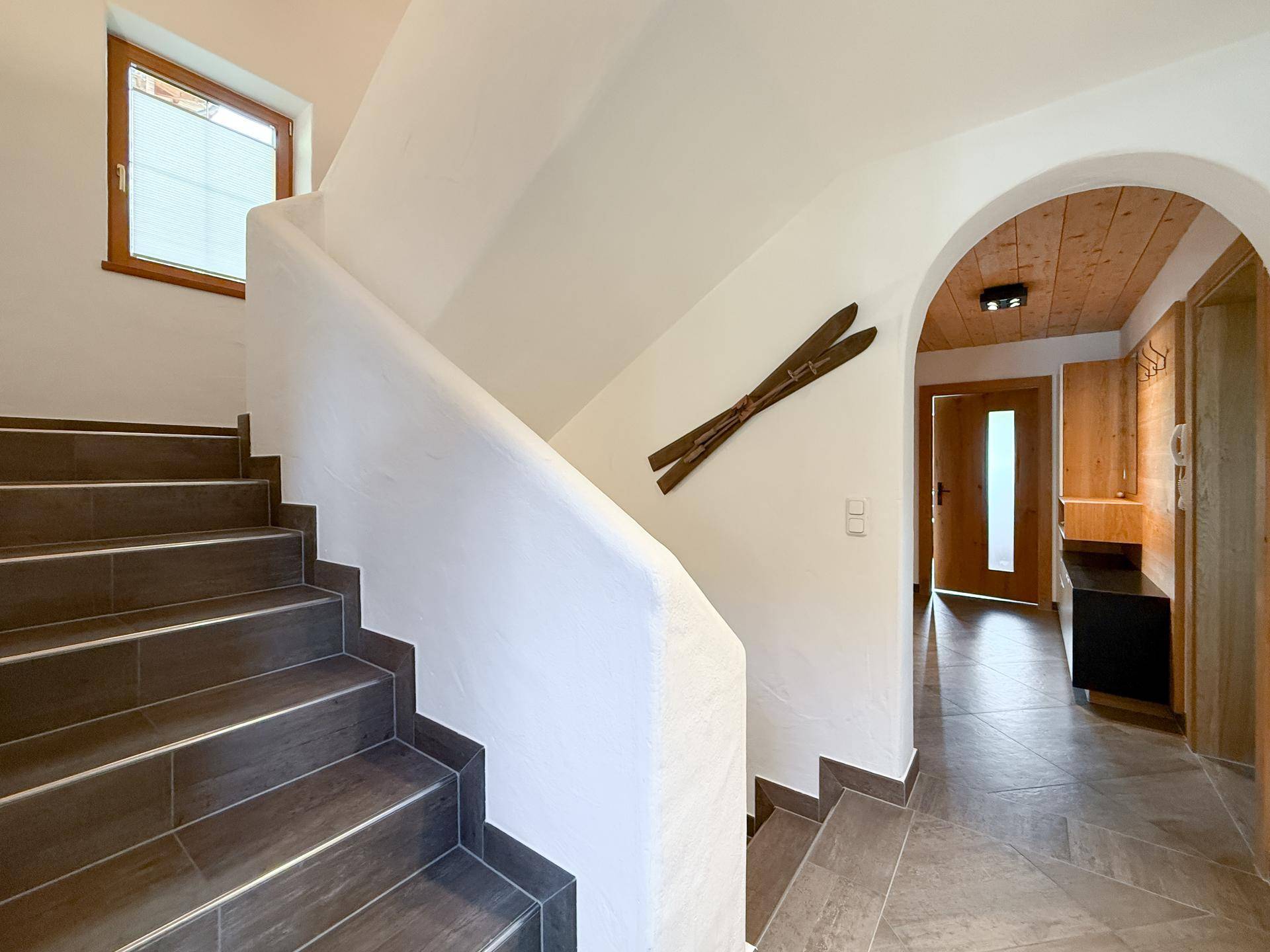 Heller Eingangsbereich mit Treppe, Holzvertäfelung und traditionellen Dekorationen.