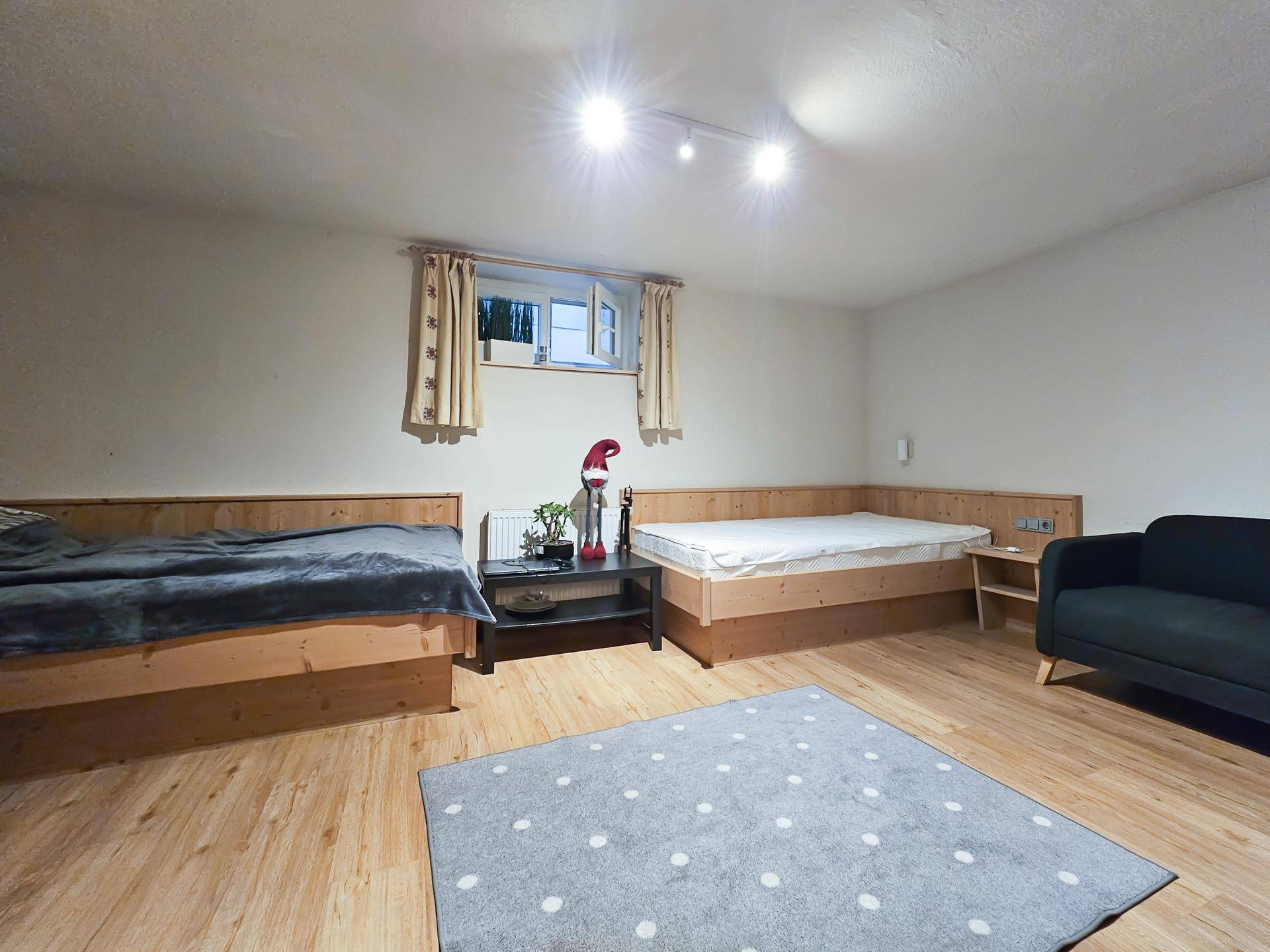 Helles Schlafzimmer mit zwei Einzelbetten, Holzboden und einem Teppich.