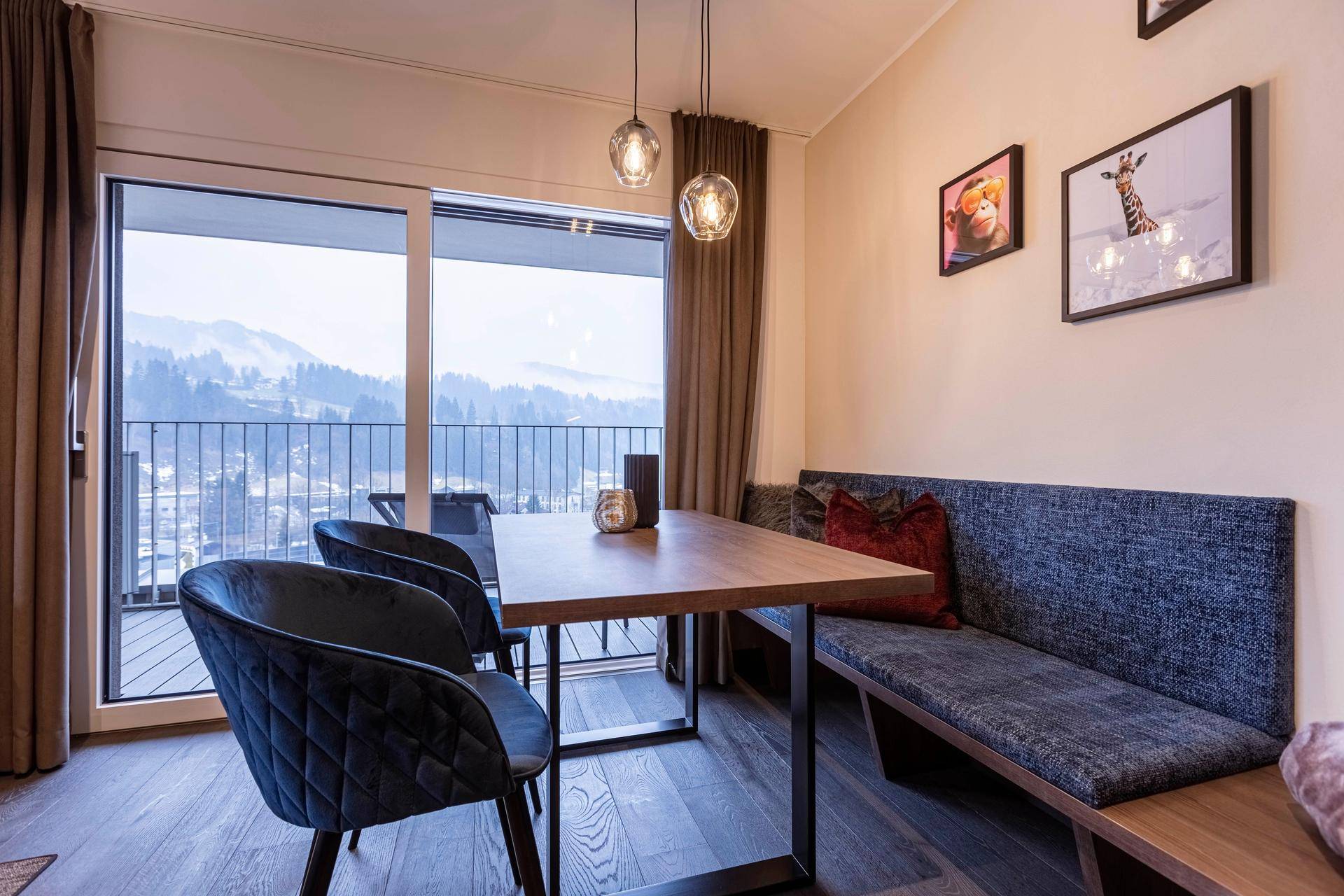 Moderner Essbereich mit gepolsterter Sitzbank und Stühlen, direkt am Fenster mit Bergblick.