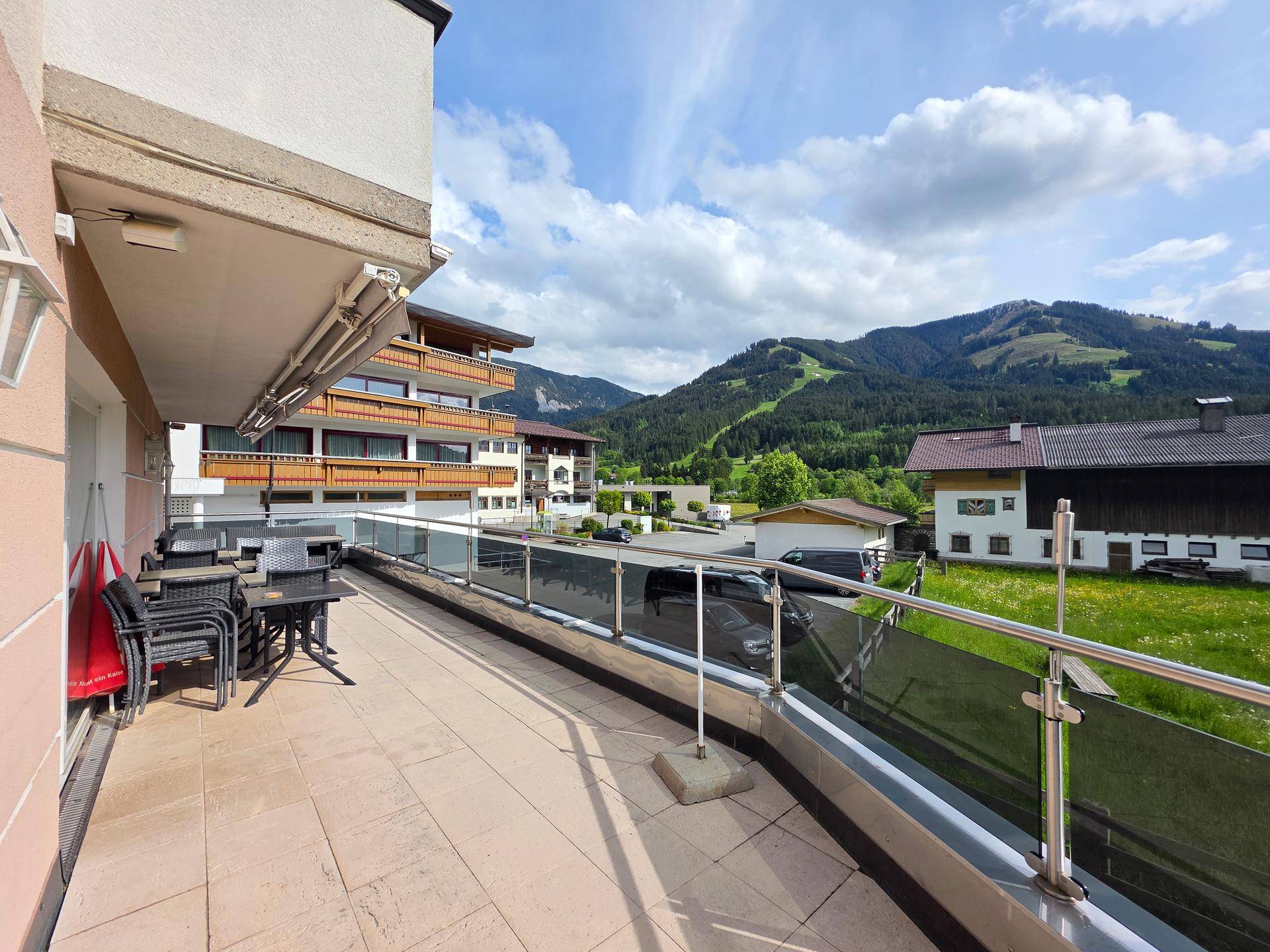 Geräumiger Balkon mit Sitzgelegenheiten und Blick auf die Straße und die umliegenden Berge.
