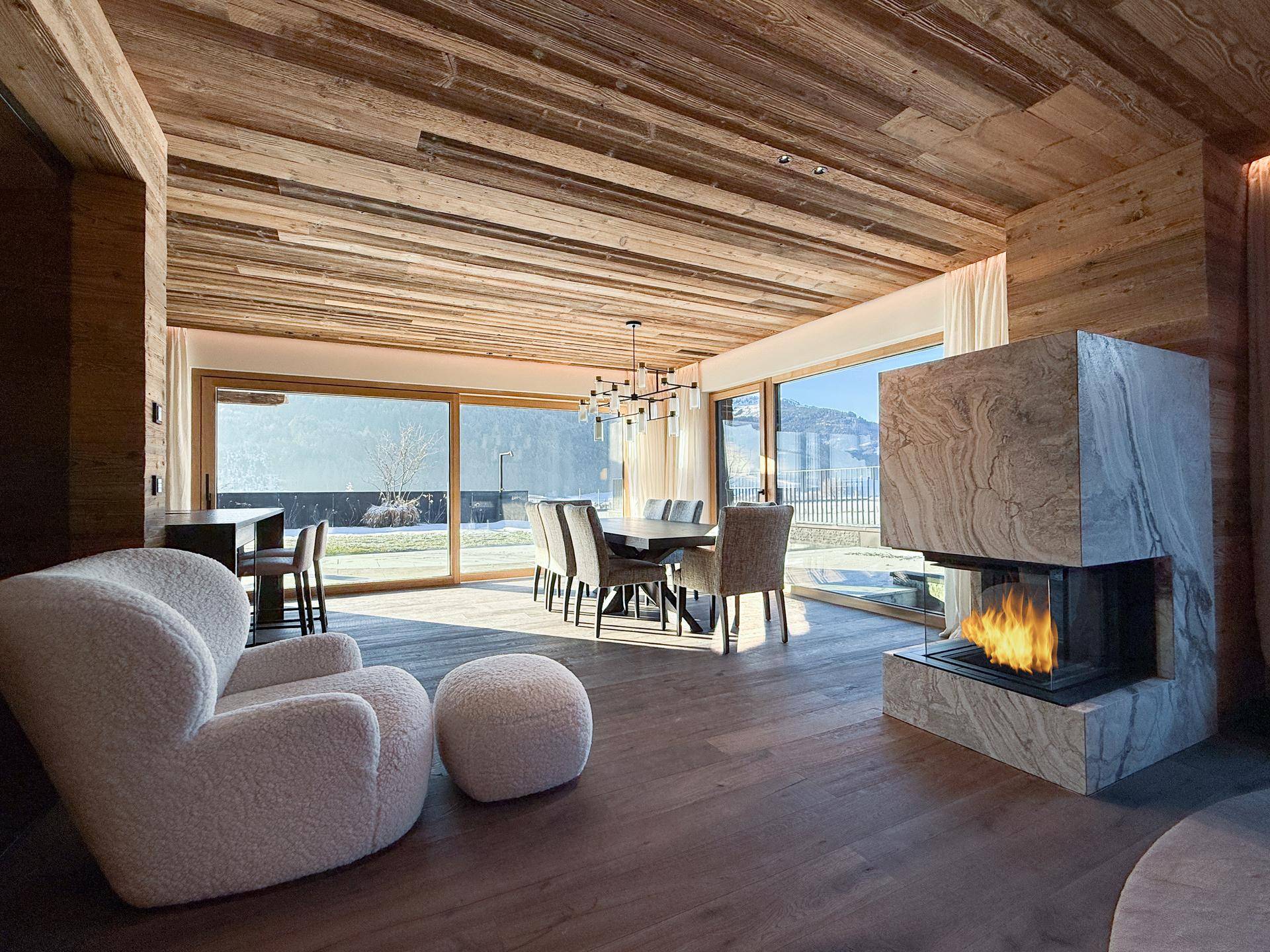 Eleganter Essbereich mit Holzboden, Kamin und Zugang zu einer Terrasse durch große Schiebetüren.