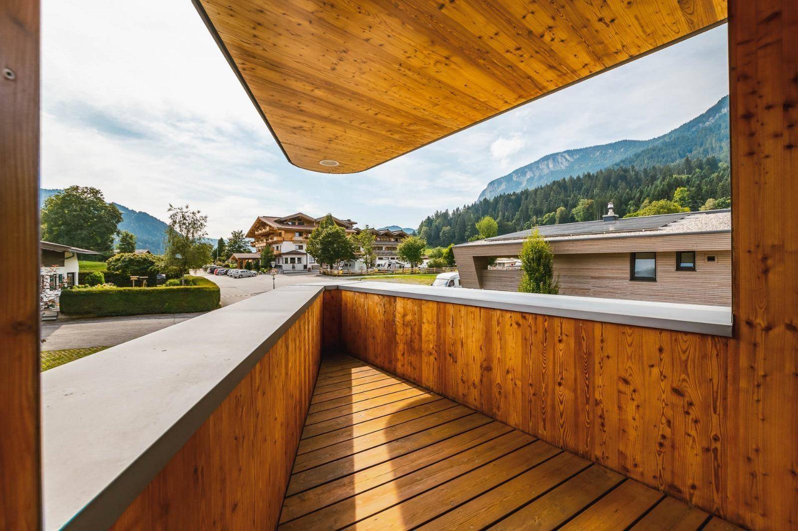 Kleiner Holzbalkon mit Blick auf die Straße und die umliegende Berglandschaft.