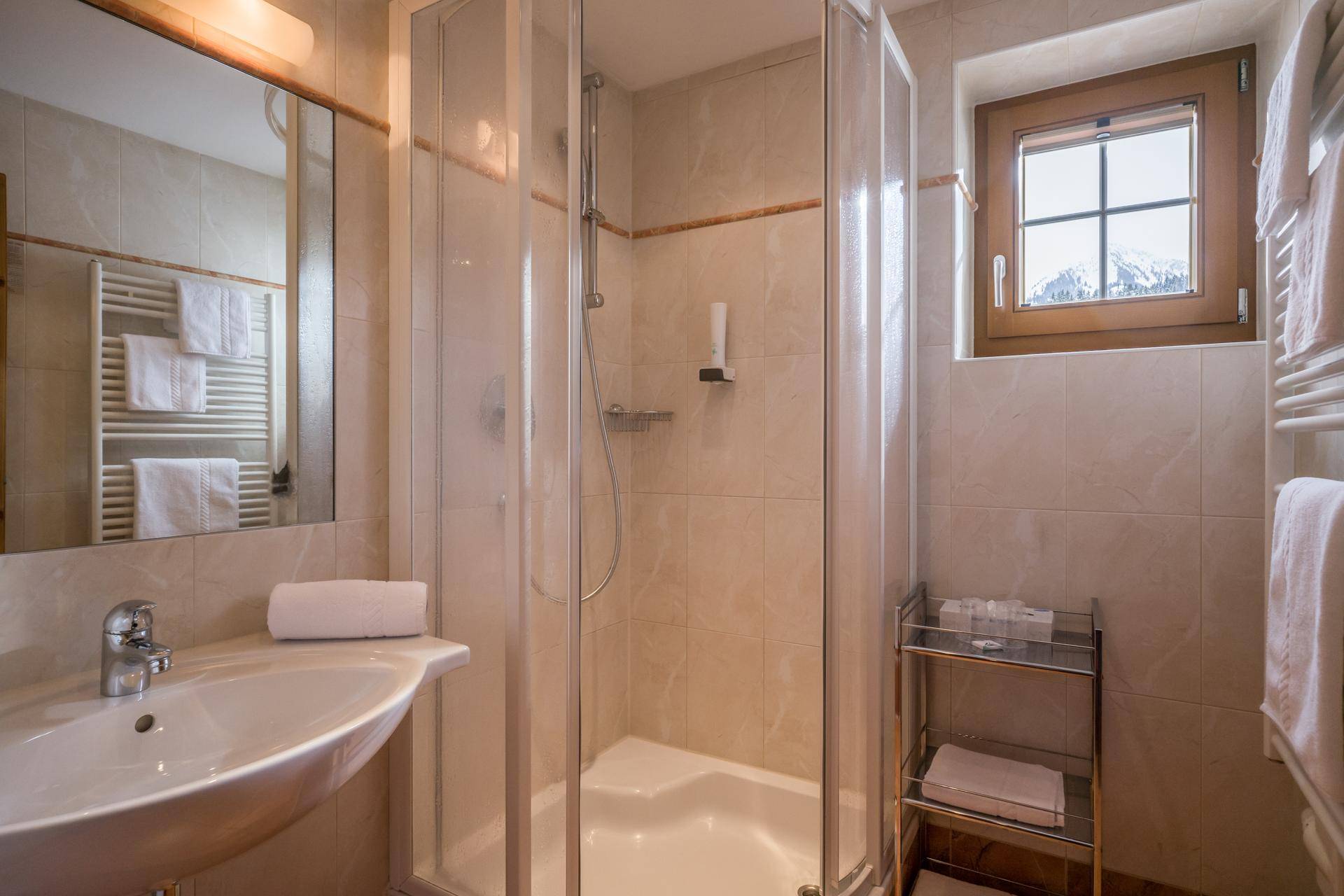 Modernes Badezimmer mit Duschkabine, Waschbecken und Fenster, das einen Bergblick bietet.