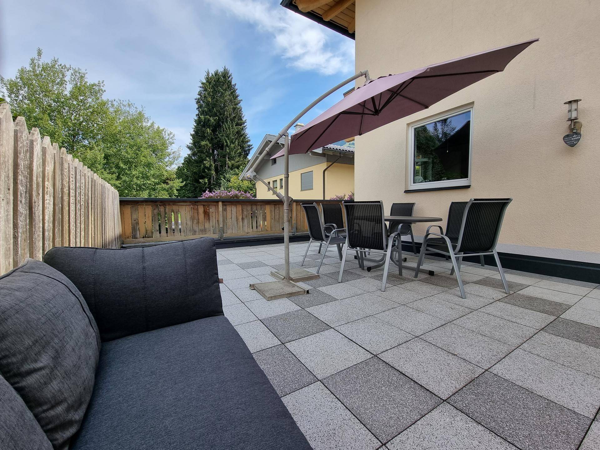 Gemütliche Terrasse mit modernen Gartenmöbeln und großem Sonnenschirm für entspannte Stunden.