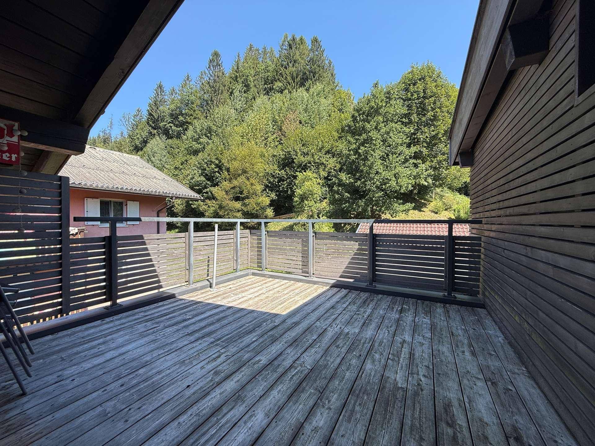 Geräumige Holzterrasse mit moderner Verkleidung und Blick ins Grüne.