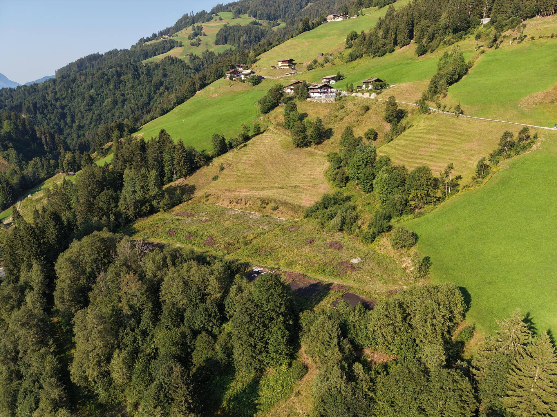 Malerische Berglandschaft mit terrassierten Feldern, Wäldern und traditionellen Häusern am Hang.