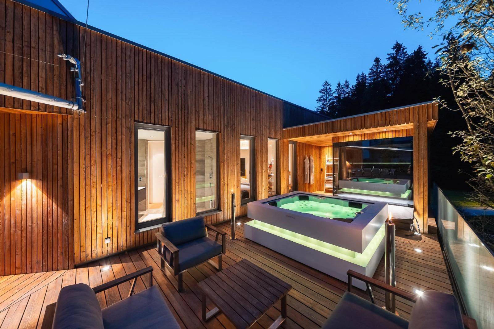 Gemütliche Holzterrasse mit modernem Whirlpool und bequemen Lounge-Sesseln für Entspannung.