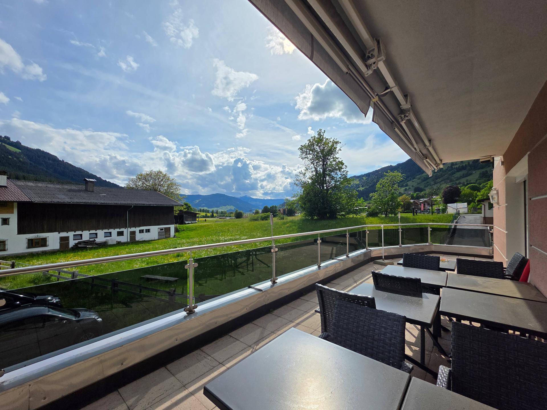 Balkon mit weitem Blick über grüne Wiesen und die beeindruckende Berglandschaft.