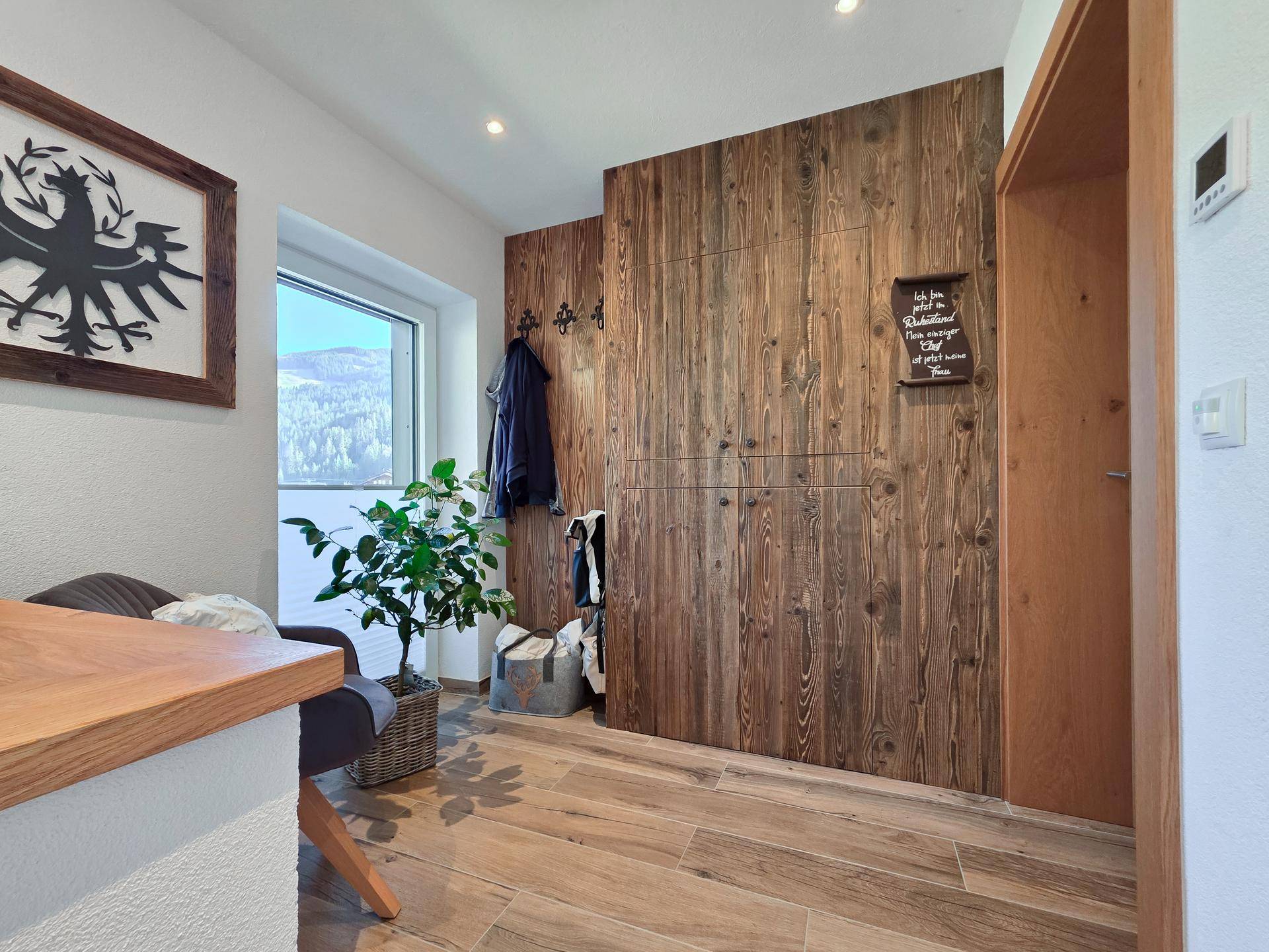 Eingangsbereich mit Holzwandverkleidung, Garderobe und Blick auf die umliegende Landschaft.