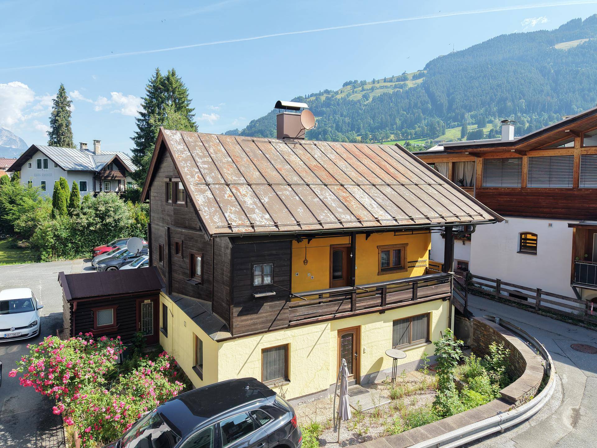Traditionelles Haus mit gelber Fassade, Holzelementen und Bergblick in ländlicher Umgebung.
