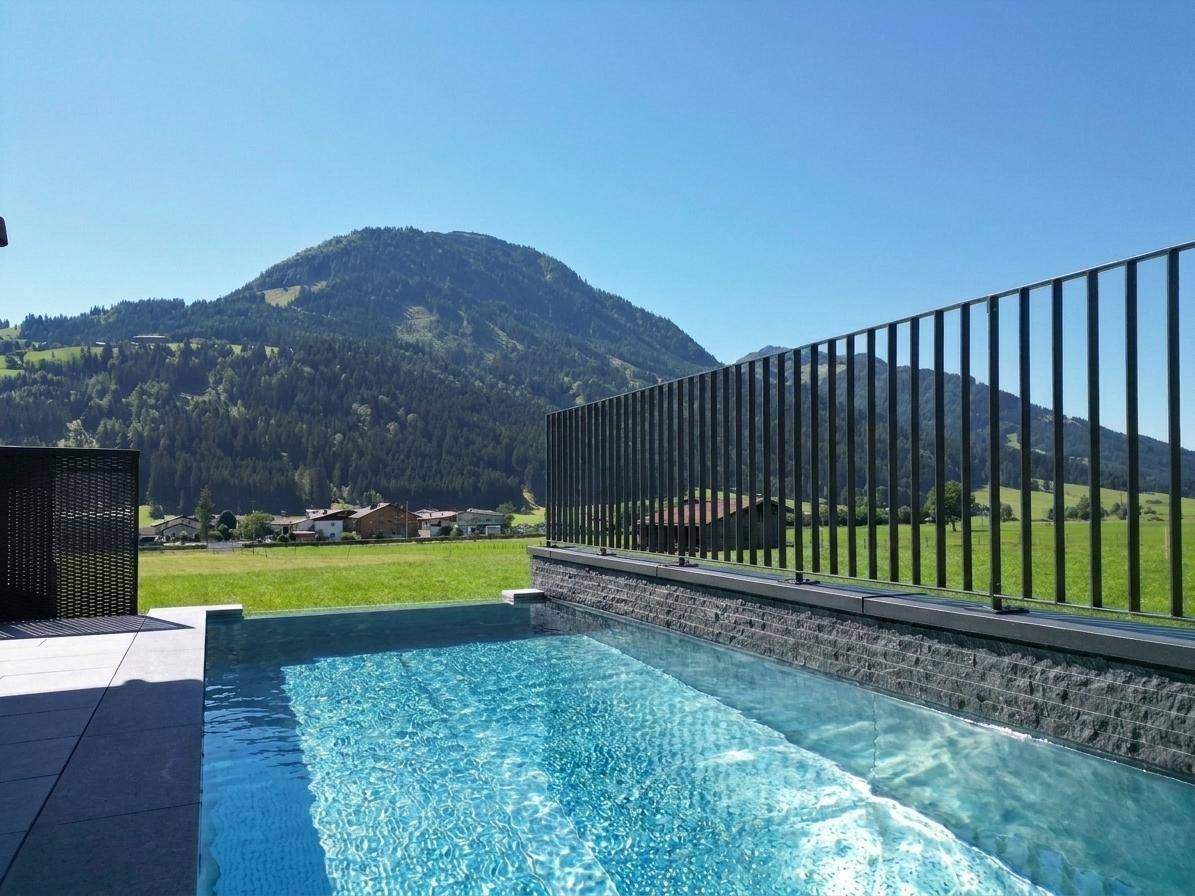 Infinity-Pool mit klarem Wasser und weitem Blick auf die umliegende Berglandschaft.