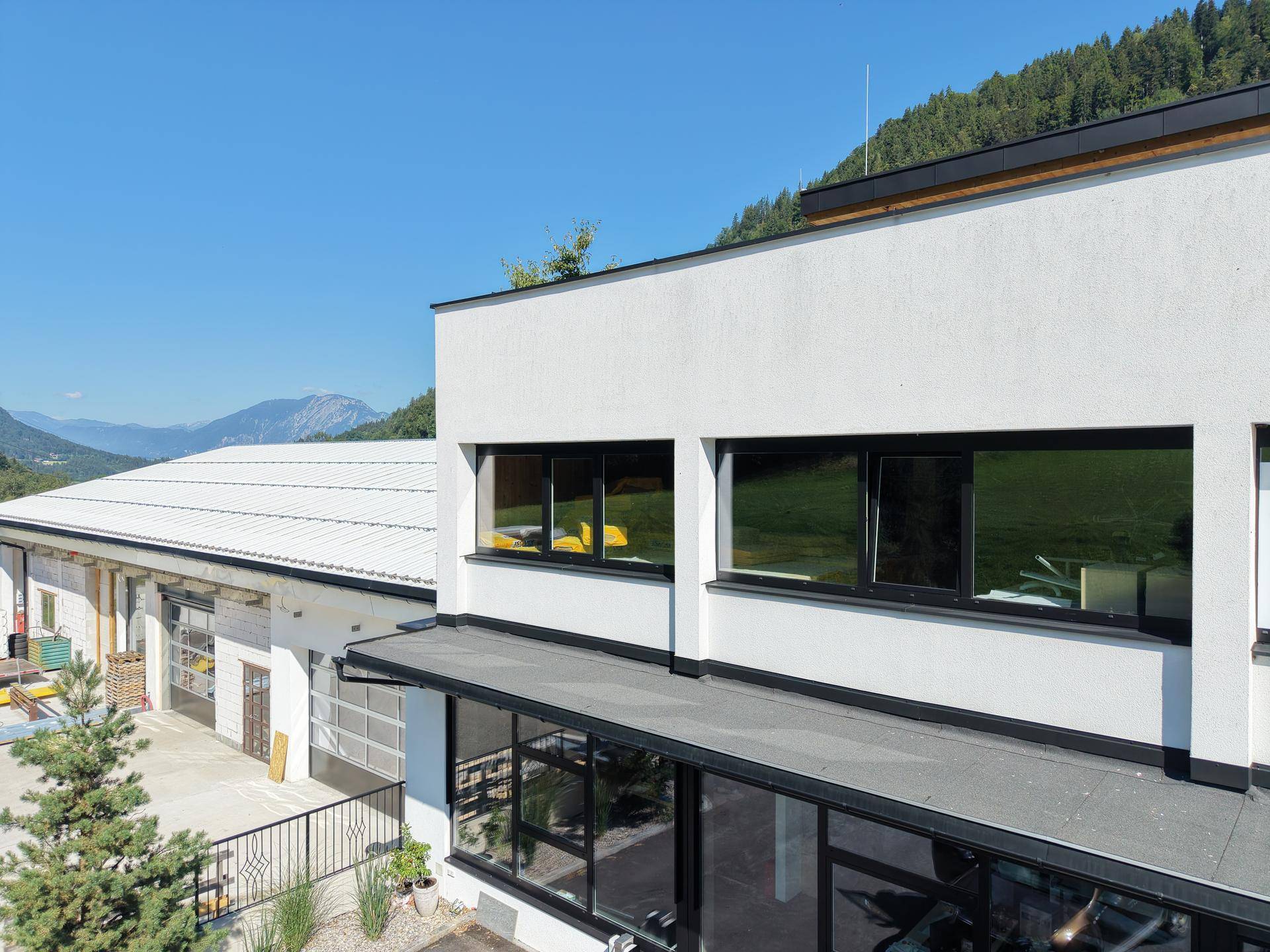 Ansicht des modernen Gebäudes mit weißer Fassade und großen Fenstern, eingebettet in eine Berglandschaft.