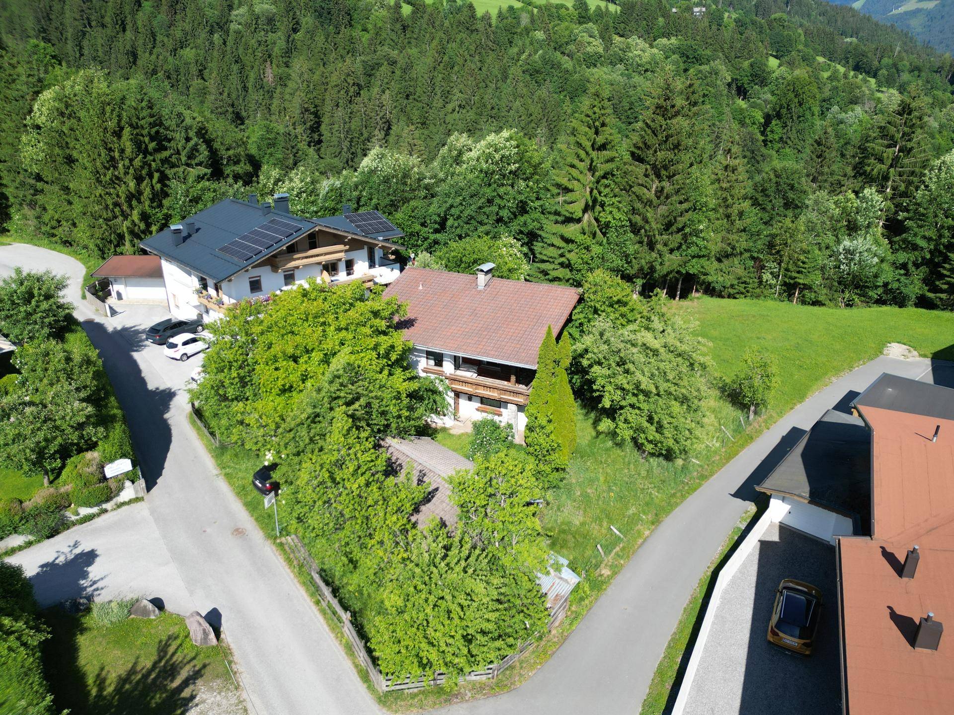 Haus in ländlicher Umgebung mit Satteldach und umgeben von üppiger Vegetation.