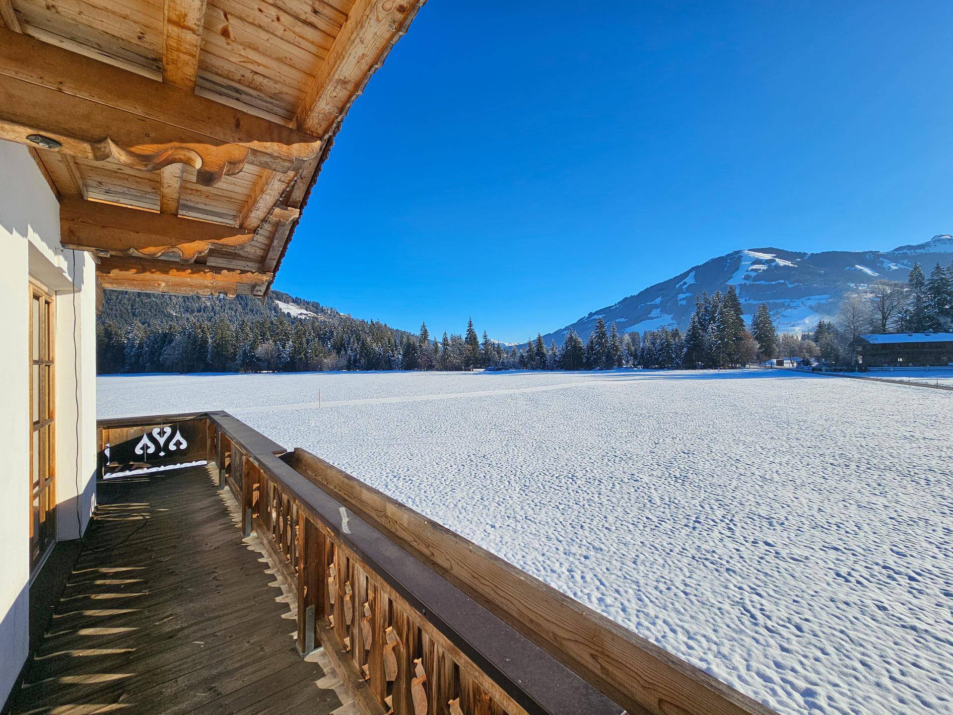 Breiter Balkon mit traditionellem Holzgeländer und einem atemberaubenden Blick auf die verschneite Bergwelt.