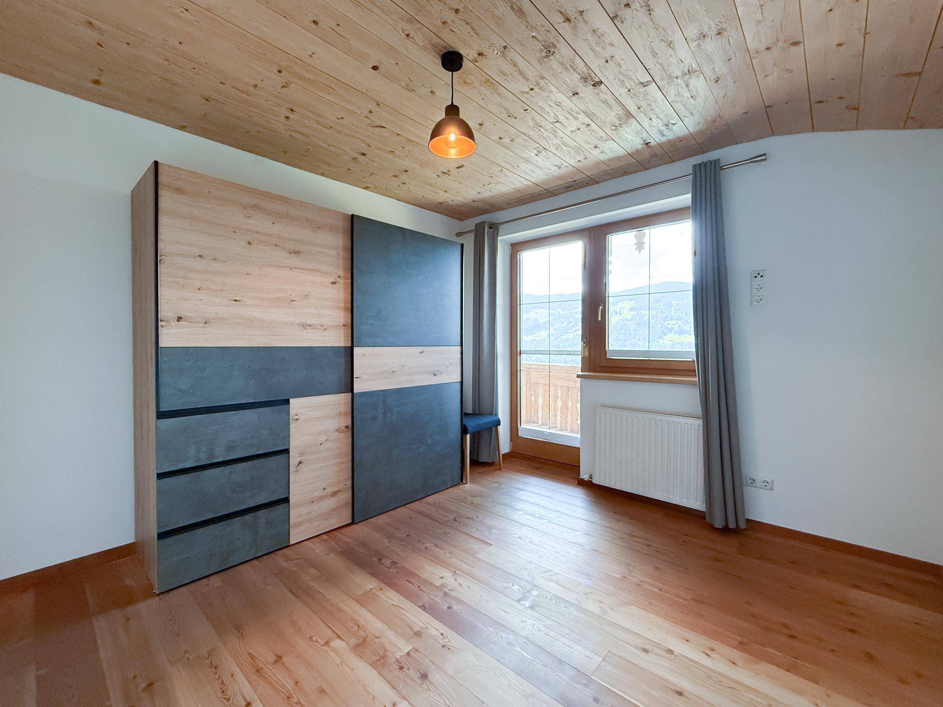 Gemütliches Schlafzimmer mit Holzboden, modernem Kleiderschrank und Bergblick.