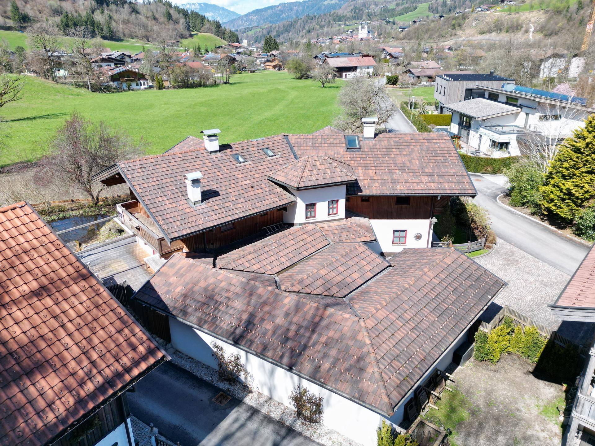 Draufsicht auf das weitläufige Anwesen mit mehreren Dächern und angrenzender Naturlandschaft.
