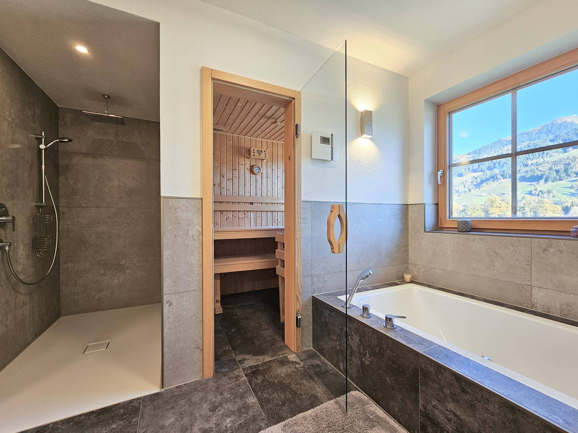 Modernes Badezimmer mit begehbarer Dusche, Badewanne und direktem Zugang zur Sauna, mit Bergblick.