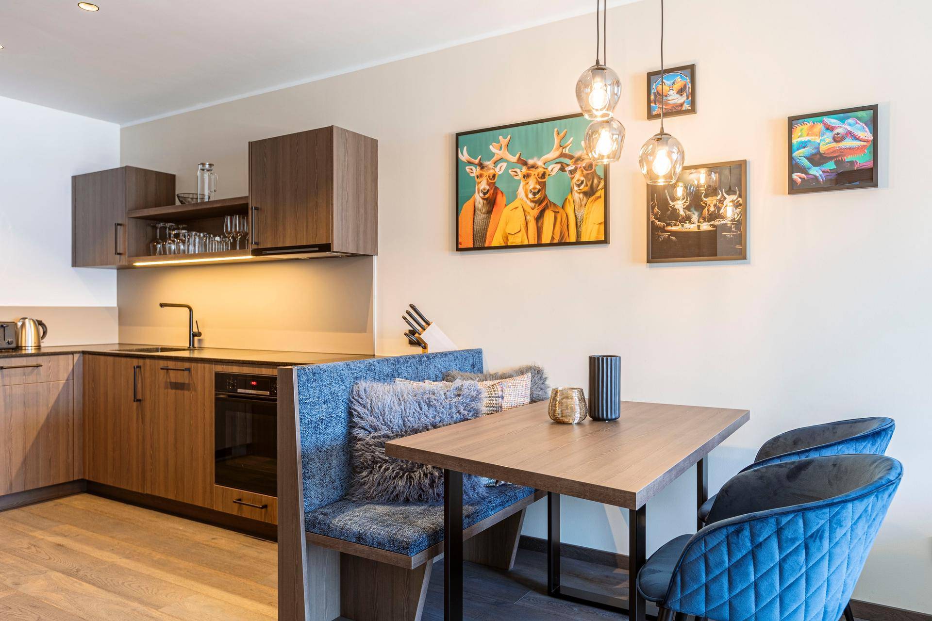 Moderne Küche mit Holzfronten und Essbereich, dekoriert mit farbenfrohen Bildern.