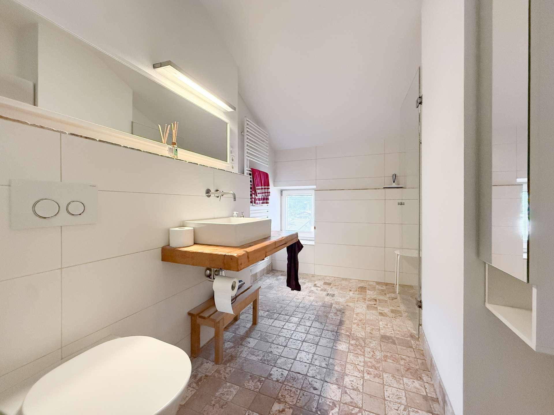 Helles Badezimmer mit modernem Waschbecken, Wand-WC und gefliestem Boden.